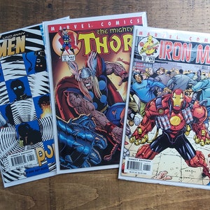 Puede incluir: Tres c&oacute;mics de Marvel Comics: "Uncanny X-Men", "The Mighty Thor" e "Iron Man". Las portadas presentan ilustraciones vibrantes de superh&eacute;roes en acci&oacute;n, con colores llamativos y composiciones din&aacute;micas. Cada c&oacute;mic est&aacute; en una funda protectora.