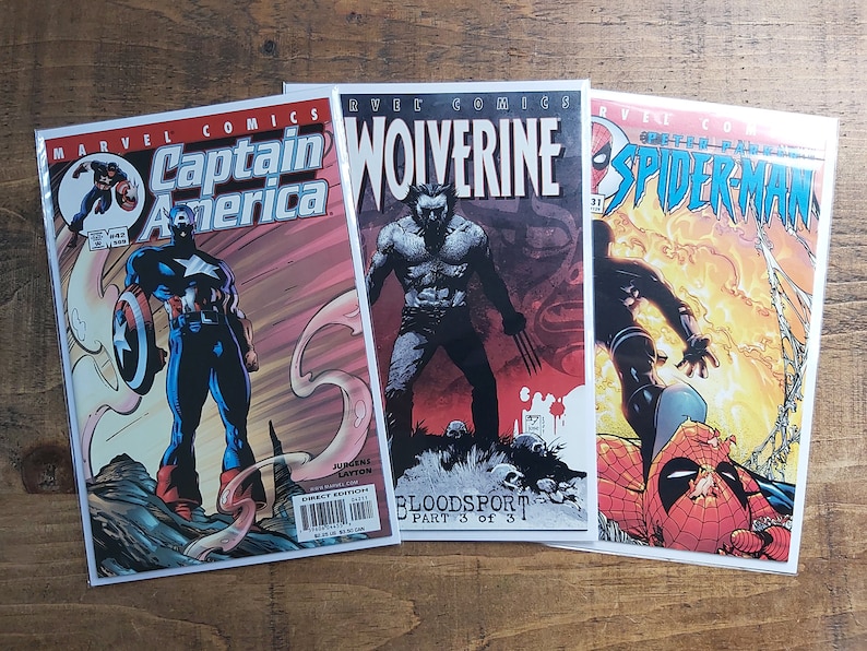 Puede incluir: Tres c&oacute;mics de Marvel con Capit&aacute;n Am&eacute;rica, Lobezno y Spiderman. El c&oacute;mic del Capit&aacute;n Am&eacute;rica muestra al h&eacute;roe con su escudo. El c&oacute;mic de Lobezno presenta al personaje con sus garras. El c&oacute;mic de Spiderman muestra al h&eacute;roe en acci&oacute;n.