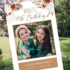 Pode incluir: Um adereço de cabine de fotos branco com uma borda marrom e decorações florais. O texto "VIOLET'S 50th Birthday" está na parte superior do adereço. A parte inferior do adereço tem uma barra marrom com o texto "#VIOLETSBIRTHDAY 8.15.2022 Austin, TX".
