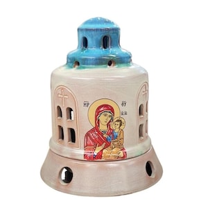 May include: A ceramic incense burner shaped like a domed building with a blue roof. The beige body features arched windows, cross cutouts, and a central icon of a figure holding a child with the Greek letters MP and OY printed on the sides.