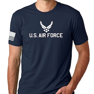 May include: A navy blue t-shirt with a white U.S. Air Force logo and a small American flag on the sleeve.