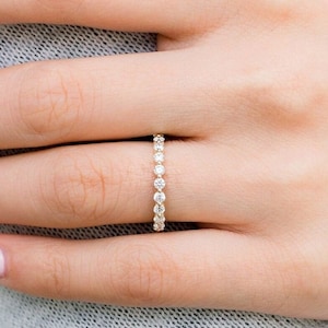 May include: A delicate gold band with a row of small, round diamonds.