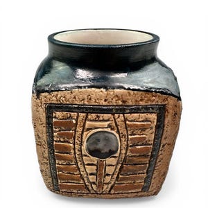 Peut inclure: Un vase en céramique artisanal avec un bord émaillé bleu foncé et un corps texturé de couleur beige. Le vase présente un motif rectangulaire avec un ovale central et des motifs en forme de briques, pour la décoration intérieure.