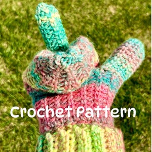 Puede incluir: Un guante tejido a mano con un diseño de hilo multicolor en tonos rosa, verde azulado, amarillo y verde. El guante muestra un gesto con el dedo medio levantado e incluye el texto blanco Crochet Pattern impreso en el centro.