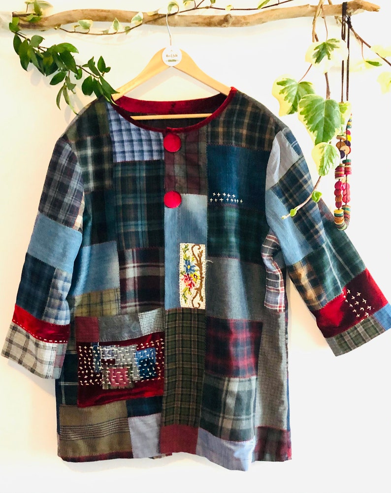 Pu&ograve; includere: Una giacca patchwork realizzata con diversi tessuti a quadri in tonalit&agrave; di blu, verde, rosso e marrone. La giacca ha un colletto e polsini in velluto rosso e presenta cuciture e ricami decorativi.