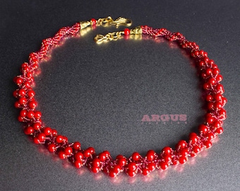 May include: A red beaded necklace with a gold clasp. The beads are arranged in a spiral pattern.