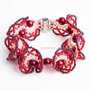 Peut inclure: Un bracelet en perles rouges et roses avec un fermoir argenté. Le bracelet est fait de petites perles et présente un motif en spirale.