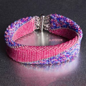 May include: A pink and blue beaded bracelet with a silver clasp. The bracelet is made of small, round beads that are woven together in an intricate pattern.