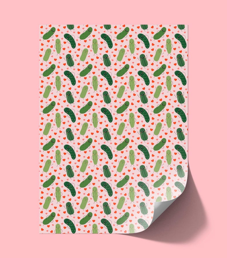 May include: A sheet of wrapping paper featuring a repeating pattern of cartoon pickles with smiling faces and small arms, interspersed with tiny red hearts on a light pink background. The paper has a curled corner showing a white underside.