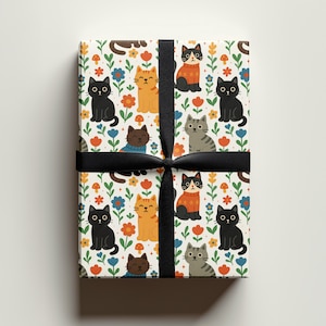 May include: Gift-wrapped present with a colorful cat pattern. The wrapping paper features cartoon cats in various colors, including black, orange, and gray, among flowers and mushrooms. A black ribbon is tied around the gift.