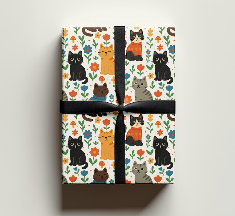 May include: Gift-wrapped present with a colorful cat pattern. The wrapping paper features cartoon cats in various colors, including black, orange, and gray, among flowers and mushrooms. A black ribbon is tied around the gift.
