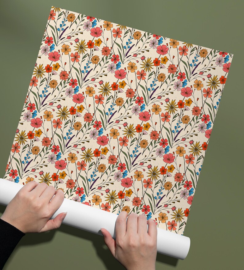 May include: A roll of wallpaper featuring a repeating pattern of wildflowers in shades of red, orange, yellow, and blue on a cream background. The design includes various small blossoms, thin green stems, and delicate leaves throughout.