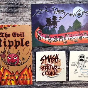 May include: A collection of four humorous art prints. One features a devil with the text "Beware of The Evil Nipple". Another says "...and they were Broommates". The others say "Smash the Patriar-Cookie" and "much scary, so boo".