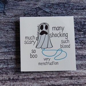 May include: A white, circular sticker featuring a cartoon ghost with a sad expression. Text around the ghost reads "much scary," "so boo," "many shocking," "such blood," and "very menstruation."