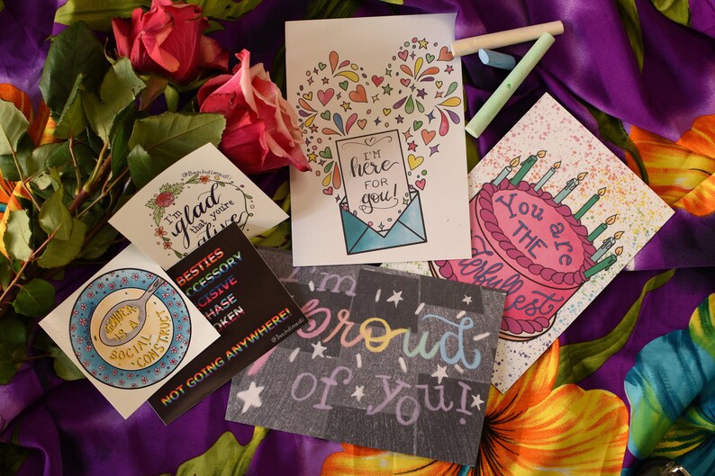 Puede incluir: Cinco tarjetas de felicitaci&oacute;n con dise&ntilde;os coloridos y mensajes escritos a mano. Las tarjetas presentan un coraz&oacute;n con fuegos artificiales, un pastel de cumplea&ntilde;os, un plato con una cuchara, una corona de flores y una pizarra con las palabras "&iexcl;Estoy orgulloso de ti!"