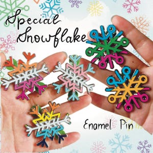 Könnte beinhalten: Fünf Emaille-Pins in Form von Schneeflocken, jede mit einem anderen Farbschema. Die Pins sind in einer Hand angeordnet, mit dem Text "Special Snowflake" und "Enamel Pin" sichtbar.