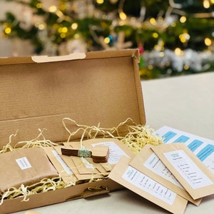 Puede incluir: Una caja de cart&oacute;n llena de sobres de papel marr&oacute;n que contienen paquetes de semillas y marcadores de plantas de madera. La caja est&aacute; abierta y el contenido es visible. Los sobres tienen el texto "Garden Time" y "Seed Starting Tips".