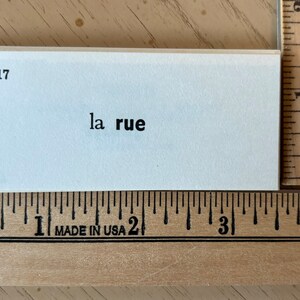 Op de afbeelding: Een witte indexkaart met het nummer 817 gedrukt in de linkerbovenhoek. De tekst "la rue" is in het zwart in het midden van de kaart gedrukt.
