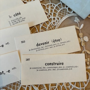 Op de afbeelding: Close-up van drie indexkaarten met Franse woorden en definities. De woorden zijn "le c&ocirc;t&eacute;", "devenir" en "construire".