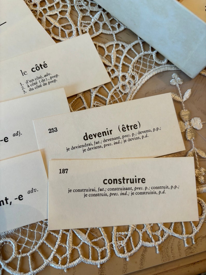 Op de afbeelding: Close-up van drie indexkaarten met Franse woorden en definities. De woorden zijn "le c&ocirc;t&eacute;", "devenir" en "construire".