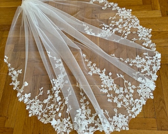 May include: A white bridal veil with delicate floral embroidery around the edge.