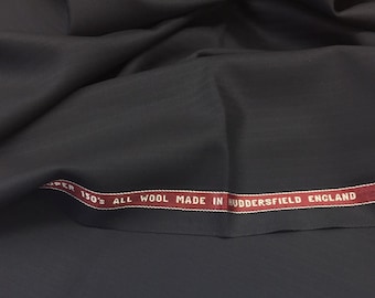 Può includere: Tessuto blu scuro con un'etichetta rossa che recita "Super 150's All Wool Made in Huddersfield England".