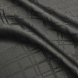 Könnte beinhalten: Schwarzer Stoff mit einem dezenten, geprägten Karomuster. Der Stoff ist gefaltet und drapiert und zeigt seine Textur.