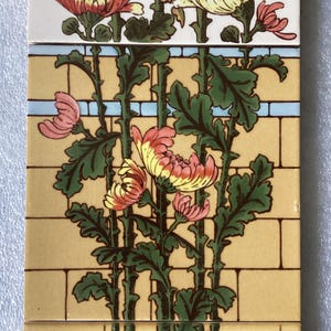 May include: Three ceramic tiles featuring a floral design. The top tile depicts white flowers with yellow and pink accents. The middle tile shows yellow flowers with pink and white accents. The bottom tile has a black vase with green stems and yellow flowers with pink and white accents.