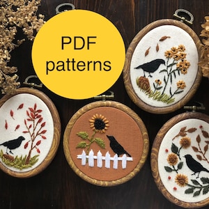 May include: Five embroidery hoop art pieces with black birds and floral designs. The hoops are on a wooden surface with the text "PDF patterns" in a yellow circle.