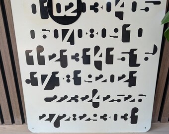 May include: A square off-white metal sign featuring a series of black stencil-style cutouts of numbers and abstract shapes. The top row prominently displays the number 02 inside a black circle, followed by the numbers 3, 4, and 5 in a stylised font.