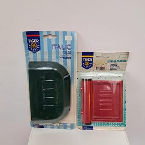Puede incluir: Dos jaboneras, una verde y otra roja, con un embalaje que dice "Italic" e "Inline". Ambas están etiquetadas como "Tiger Plastics" y están hechas de plástico.