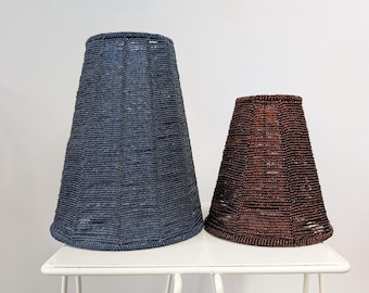 May include: Two conical lampshades with a beaded texture. The larger lampshade is dark blue, and the smaller lampshade is dark brown. Both feature vertical paneling and a consistent beaded surface finish throughout their exterior structures.
