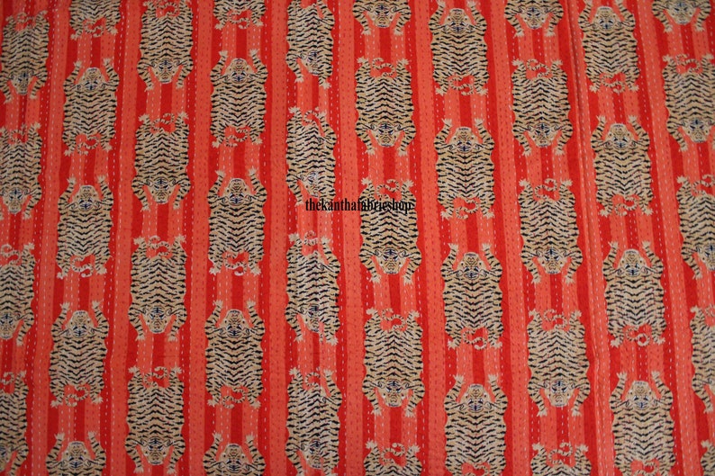 May include: Red fabric with a repeating pattern of black and white tiger stripes. The tigers are facing upwards and are arranged in vertical rows.