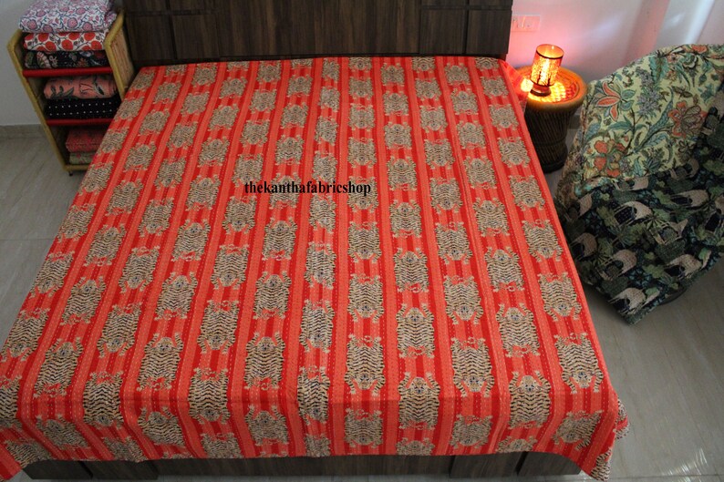 May include: Red and white striped kantha quilt with a repeating pattern of small, stylized animals. The quilt is made of cotton and has a hand-stitched look. The text "thekanthafabricshop" is visible in the center of the quilt.