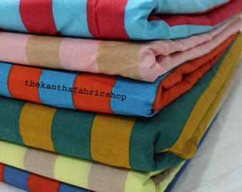 Puede incluir: Una pila de seis edredones de tela doblados con rayas verticales en varias combinaciones de colores, incluyendo rojo y azul claro, rosa y beige, naranja y azul, verde oscuro y amarillo mostaza, amarillo claro y beige, y azul y rojo.