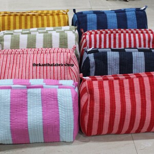 May include: A collection of eight rectangular zipped pouches featuring vertical striped patterns in various colours including yellow, green, red, blue, pink, and light blue. Each pouch has a quilted texture and thekanthafabricshop text.