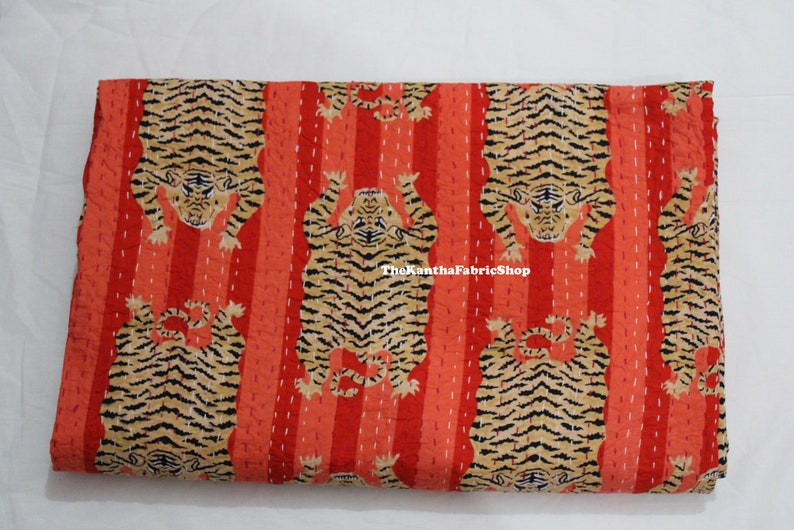 May include: Red and orange kantha quilt with a repeating pattern of black and brown tigers. The quilt has a striped background and the text "TheKanthaFabricShop" is visible in the center.