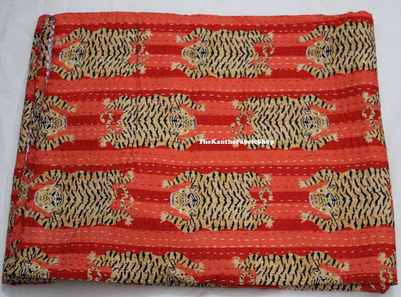 May include: Red and brown kantha quilt with a repeating pattern of tigers. The quilt is made of cotton and has a hand-stitched design. The text "TheKanthaFabricShop" is visible in the lower center of the quilt.