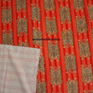 May include: A red and white kantha quilt with a repeating pattern of tigers. The quilt is made of cotton and has a hand-stitched design. The quilt is reversible, with a white side and a red side.