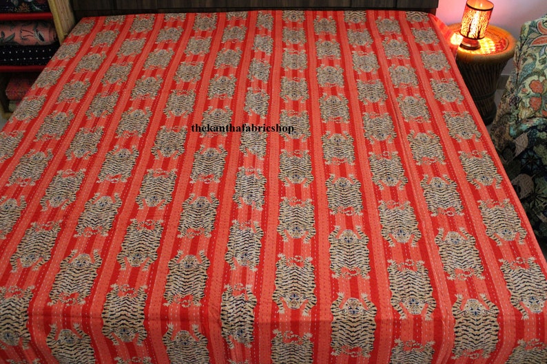 May include: Red and white striped kantha quilt with a repeating pattern of tigers. The quilt has a hand-stitched design and is made of cotton. The text "thekanthafabricshop" is printed in the center of the quilt.