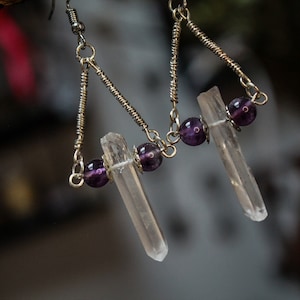 Könnte beinhalten: Silberne Ohrringe mit klaren Quarzkristallen und Amethystperlen.