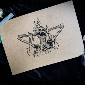 Könnte beinhalten: Schwarz-Weiß-Illustration eines Skeletts in Flammen, die Arme hinter dem Kopf, auf beigem Papier. Das Bild ist vor einem dunklen Hintergrund mit Kristallen und getrockneten Blumen platziert. Das Kunstwerk hat ein gotisches Thema.
