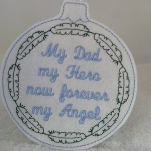 May include: White felt ornament with blue embroidery that reads "My Dad my Hero now forever my Angel" surrounded by a wreath of green feathers.