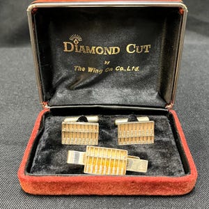 May include: A set of gold-toned cufflinks and a matching tie bar, each featuring a miniature abacus design. The items are presented in a black velvet-lined box with the text Diamond Cut by The Wing On Co., Ltd. printed in gold on the inner lid.