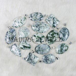 May include: A collection of gemstone pendants in various shapes, including oval, teardrop, and square. The pendants feature a white and green pattern, set in silver-colored metal. The image includes the text "MADINA JEWELZ".