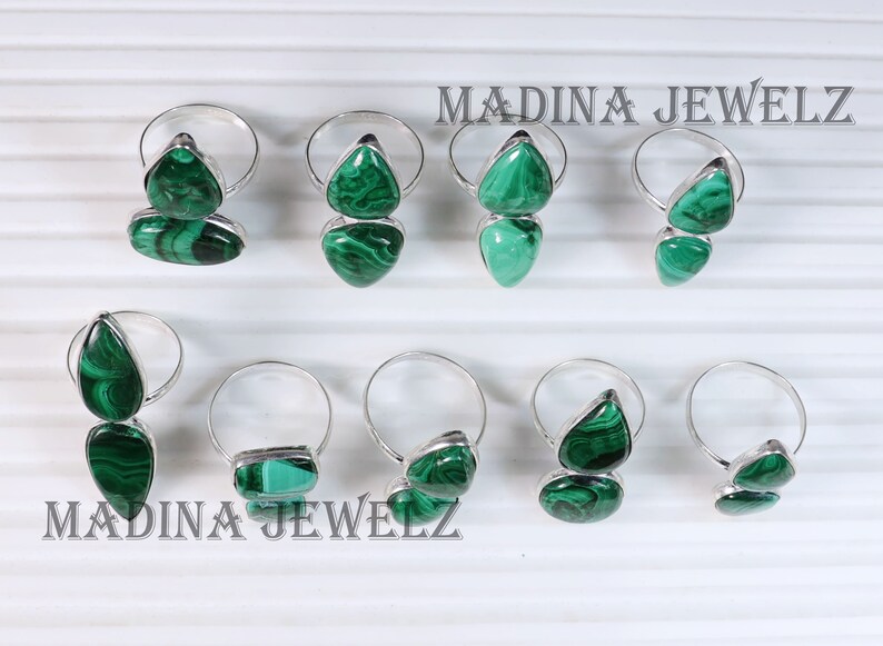 Pu&ograve; includere: Otto anelli d'argento con pietre di malachite verde. Gli anelli presentano due pietre ciascuno, una pi&ugrave; grande dell'altra. Le pietre sono di un verde intenso con un motivo marmoreo. Gli anelli sono disposti in due file di quattro. Il testo "MADINA JEWELZ" &egrave; visibile nella parte superiore dell'immagine.