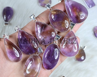 May include: A collection of amethyst and citrine gemstone pendants with silver bail settings. The pendants are teardrop and oval shaped and have a variety of purple and yellow hues.