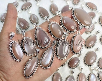 Puede incluir: Una colección de colgantes ovalados y en forma de lágrima con cabujones de piedra lunar de color marrón claro lisos, engastados en monturas de metal plateado decorativas con bordes perlados. Cada colgante incluye una reasa.
