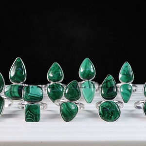 Pu&ograve; includere: Una collezione di dieci anelli d'argento con pietre preziose di malachite verde. Gli anelli presentano una variet&agrave; di forme, tra cui gocce e quadrati.