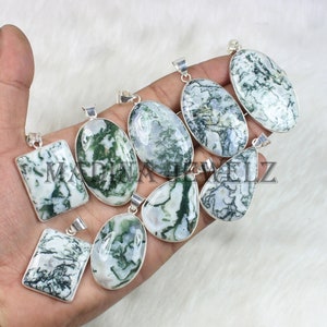 May include: A collection of moss agate pendants in various shapes, including oval, rectangular, and teardrop. Each pendant features a silver-colored bail and a unique pattern of green and white marbling. The text "MADINAVELZ" is visible on some of the pendants.